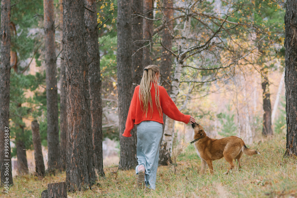 Young woman walking with her dog in autumn mountains