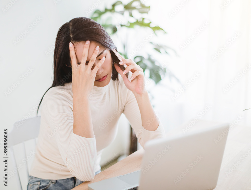 stressed young woman working on laptop and talking on the phone in the home office stressed young woman working on laptop and talking on the phone in the home office