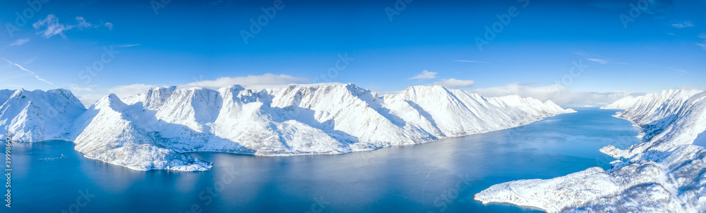 Aerial view of snow capped mountains and fjord during the cold arctic winter, Oksfjord, Troms og Finnmark Aerial view of snow capped mountains and fjord during the cold arctic winter, Oksfjord, Troms og Finnmark
