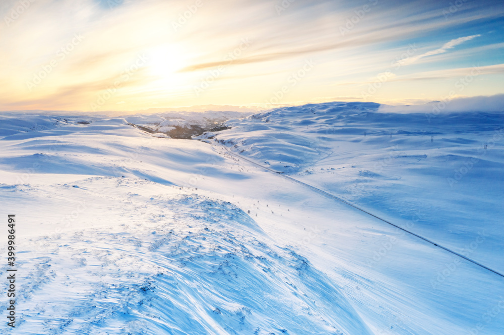 Aerial view of empty road across mountains covered with snow lit by sunrise, Sennalandet, Alta, Troms og Finnmark, Arctic Aerial view of empty road across mountains covered with snow lit by sunrise, Sennalandet, Alta, Troms og Finnmark, Arctic