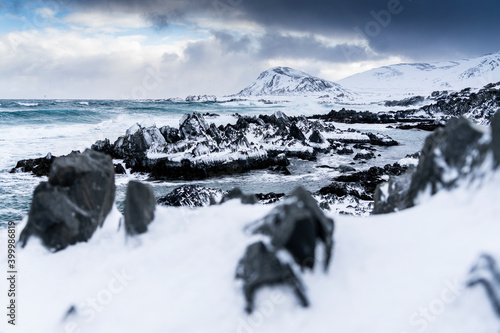 Cliffs covered with snow on coastline of the cold Barents Sea, Sandfjorden, Arctic Ocean, Varanger Peninsula, Finnmark photo