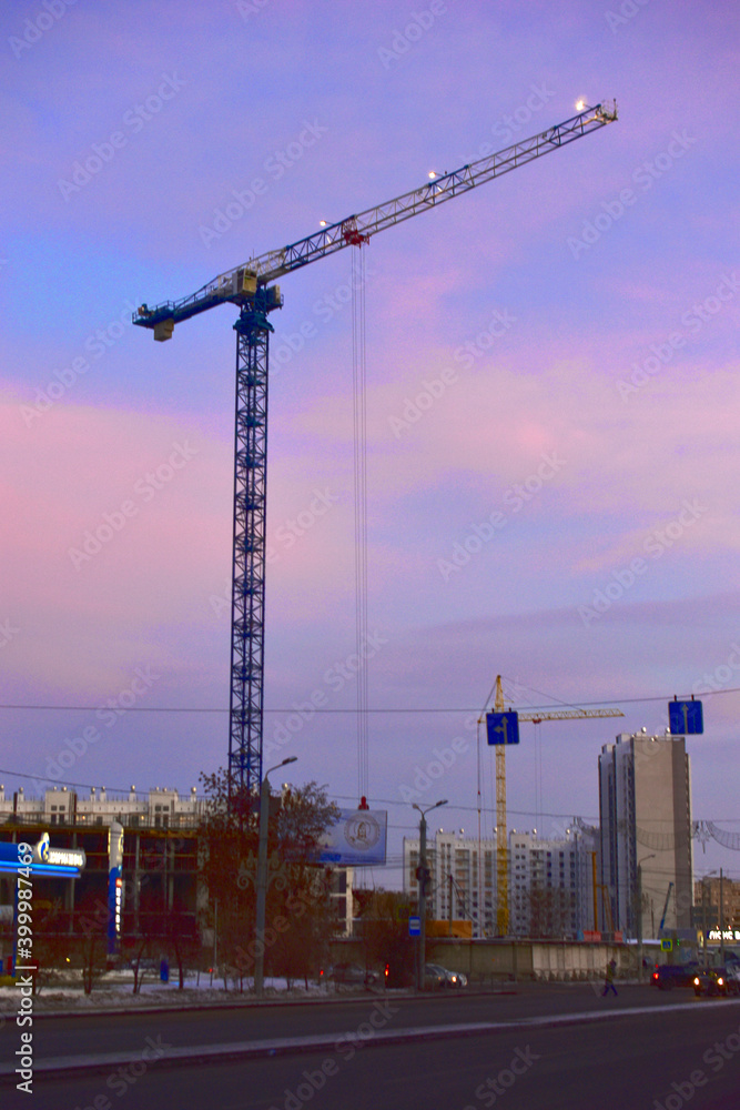 Construction of houses with tower cranes in the evening city