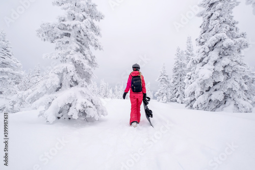 Snowboarder female walking through winter forest carrying snowboard. Powder Day. Walking throw deep snow, freeride on winter holiday