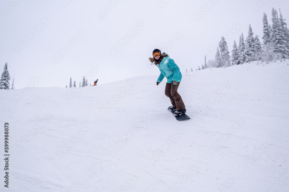Snowboarder female riding on winter snow cowered slop on snowboard. Powder Day, winter holiday in ski resort