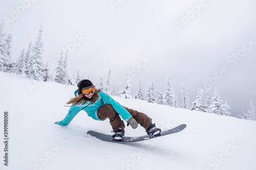 Snowboarder female riding down slop in winter ski resort , doing lazy boy snowboarding trick