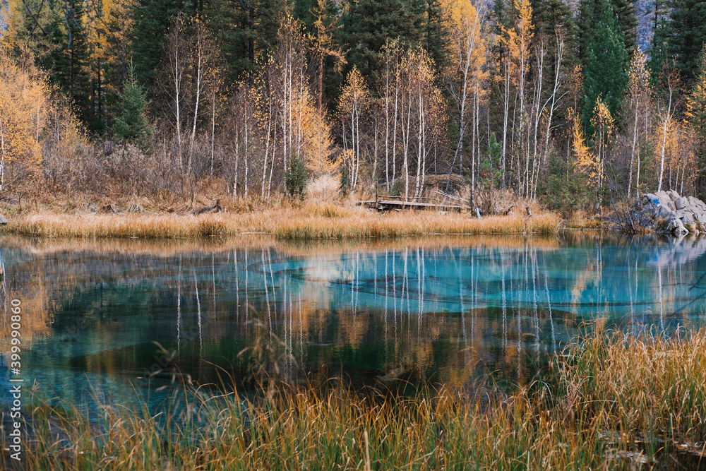 Obraz premium Blue Geyser Lake with autumn trees reflection in mountains