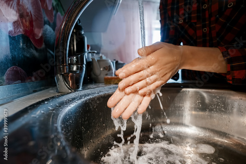 Female washing her hands in water under tap
