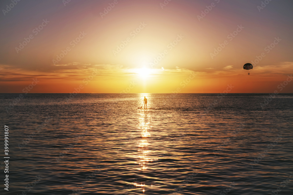 Obraz premium Sup surfer silhouette on beautiful sea sunset