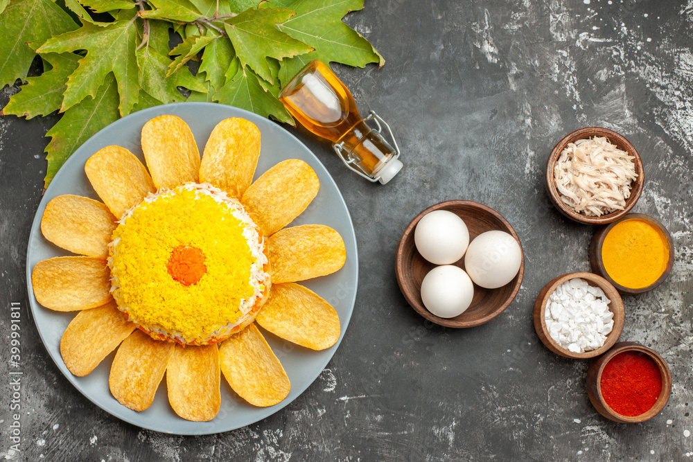 top view of salad with oil bottle bowl of eggs and leaves on side with herbs near to it on dark grey table top view of salad with oil bottle bowl of eggs and leaves on side with herbs near to it on dark grey table