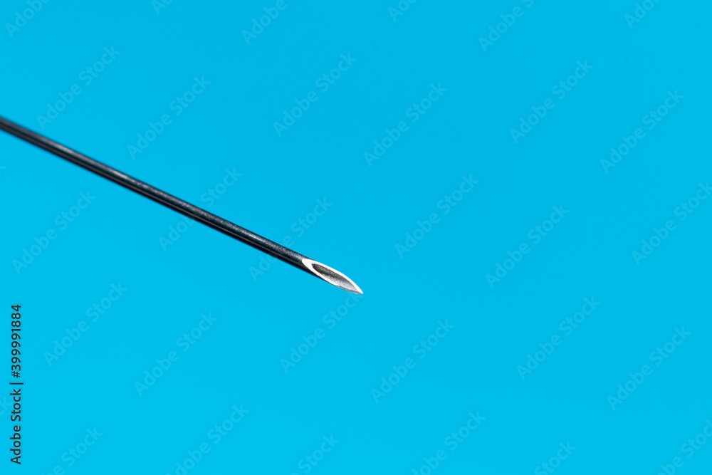 Macro photo of a medical needle from a syringe on a blue background. The concept of vaccination in health care Macro photo of a medical needle from a syringe on a blue background. The concept of vaccination in health care