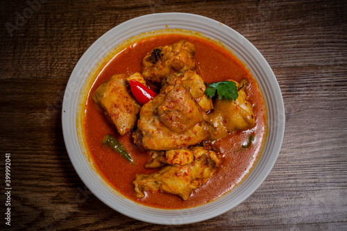 Ayam Kalio Padang or wet saucy chicken rendang top view on wooden background.