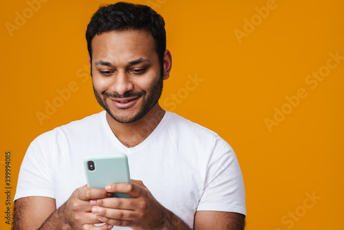 Asian happy unshaven man smiling while using mobile phone