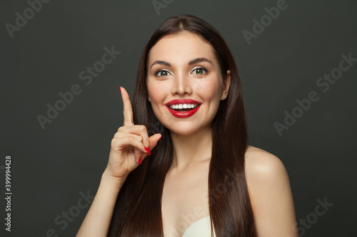 Happy woman pointing up on black banner background