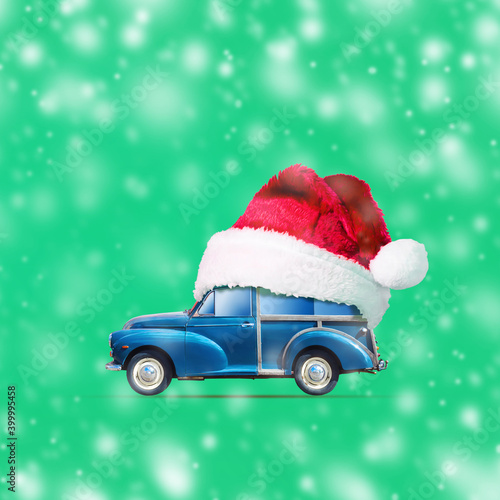 Retro car in Santa Claus Hat on a green background. Snow effect. Christmas background. F