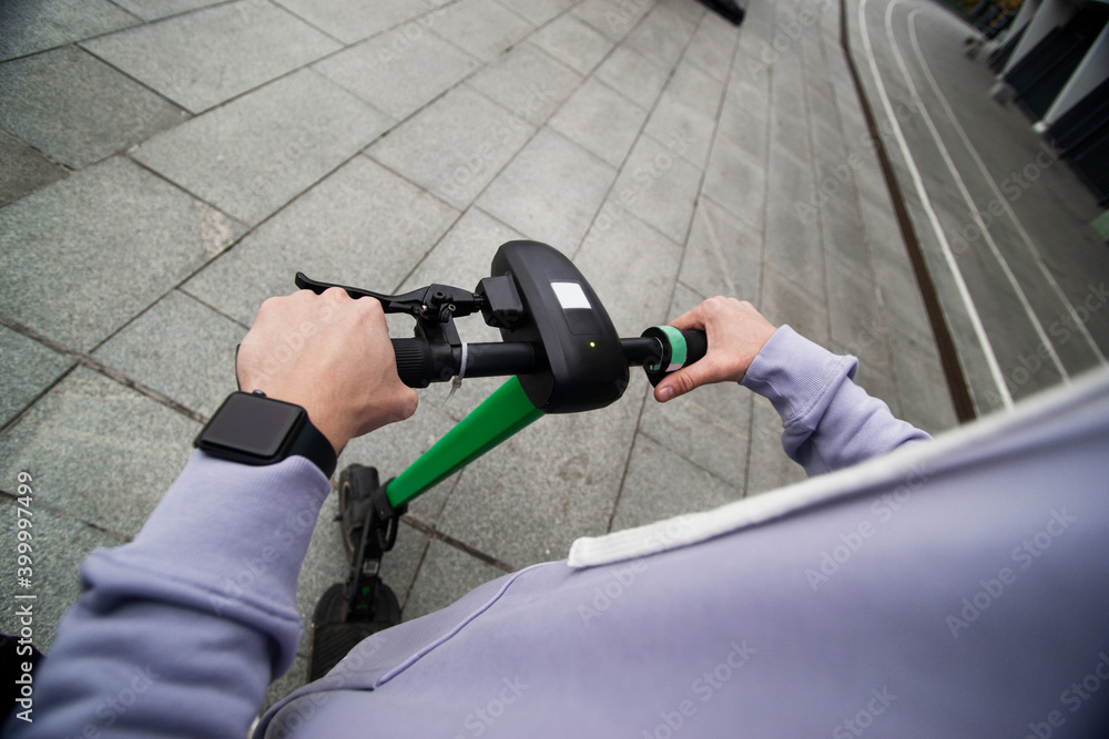 Obraz premium Male hands holdind steering wheel of e-scooter. Top view. Easy driving concept. First person view. Guy driving on electric around city. Eco-friendly transport concept.