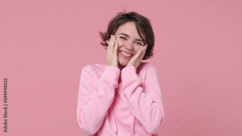 Excited brunette young woman 20s years old in basic streetwear hoodie posing isolated on pastel pink background studio. People lifestyle concept. Put hands on chest ask who me doing winner gesture Excited brunette young woman 20s years old in basic streetwear hoodie posing isolated on pastel pink background studio. People lifestyle concept. Put hands on chest ask who me doing winner gesture