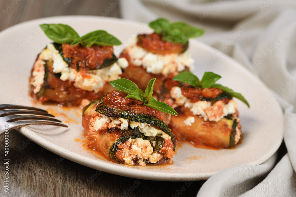 Baked zucchini rolls stuffed with ricotta and basil under tomato-onion-carrot gravy 