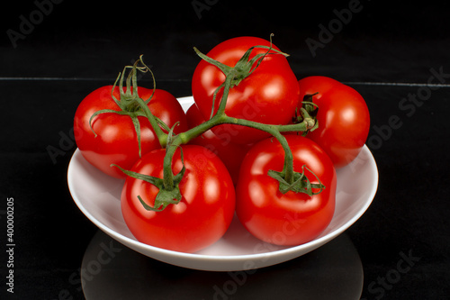 juicy ripe tomatoes on a white plate close up