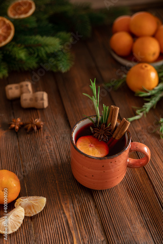 Mulled wine winter hmemade drink for holiday celebration with orange mandarins, tangerin on the wooden table