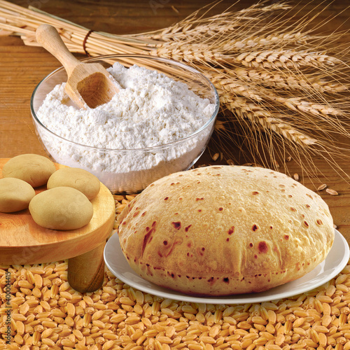 Wheat flour, Chapati, Roti, Bunch of wheat ears, dried grains, flour in terracota bowl. Cereals harvesting, bakery products. photo