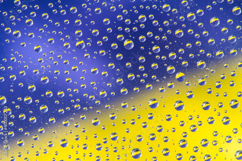 Water drops on yellow blue background. Top view. Closeup.