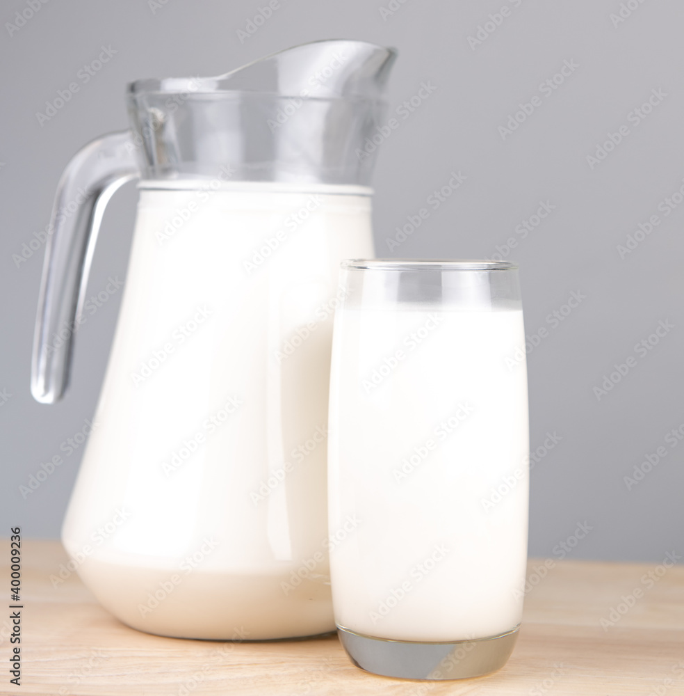 A jug and bottle of milk glass on a wooden table on background..Raw milk is high in calcium and protein to drink for all ages..Milk consumption nutritious and healthy dairy products concept.. A jug and bottle of milk glass on a wooden table on background..Raw milk is high in calcium and protein to drink for all ages..Milk consumption nutritious and healthy dairy products concept..