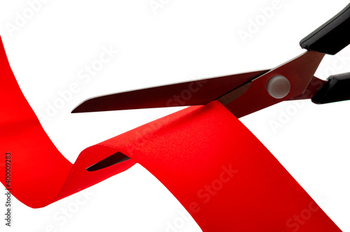 Grand opening ceremony, symbolic project launch, bureaucracy and inauguration event concept with scissors cutting red satin tape or ribbon isolated on white background and clipping path cutout photo