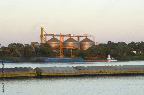 Chatas transportando soja na Hidrovia do Rio Madeira em Porto Velho e silos de armazenagem de grãos no fundo photo