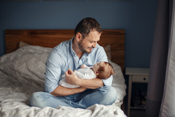 Fathers Day. Middle age Caucasian father with sleeping newborn baby girl. Parent holding child daughter son on hands. Authentic lifestyle parenting moment. Single dad family home life.