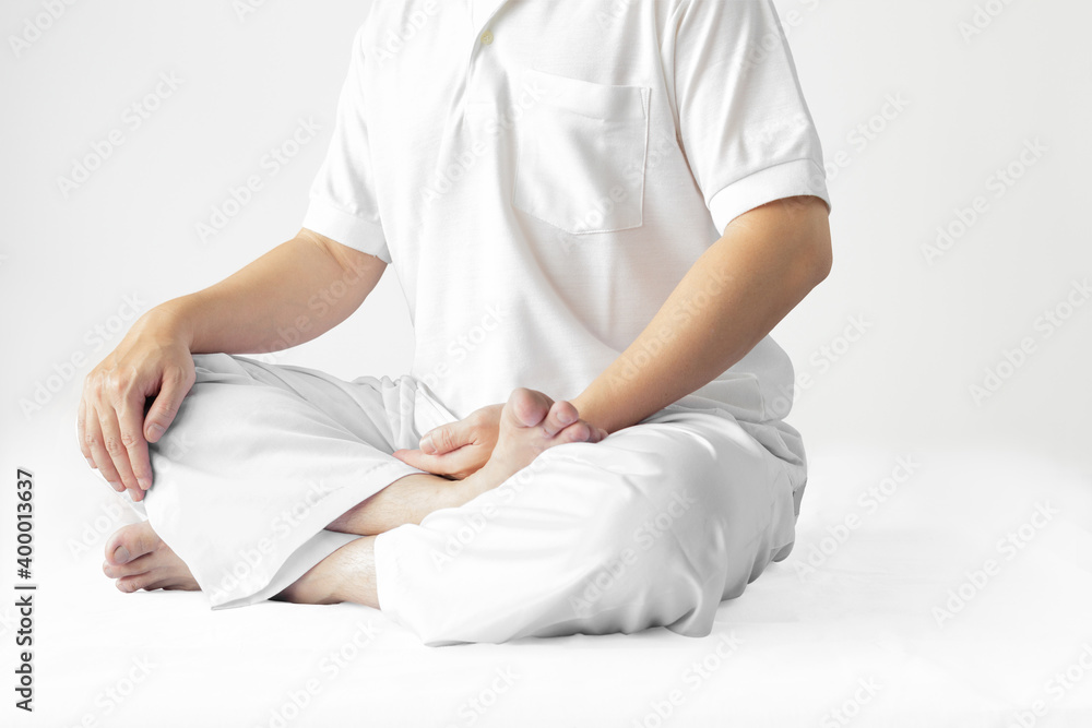 A man in a white robe meditating against a white backdrop with a clipping path. A man in a white robe meditating against a white backdrop with a clipping path.