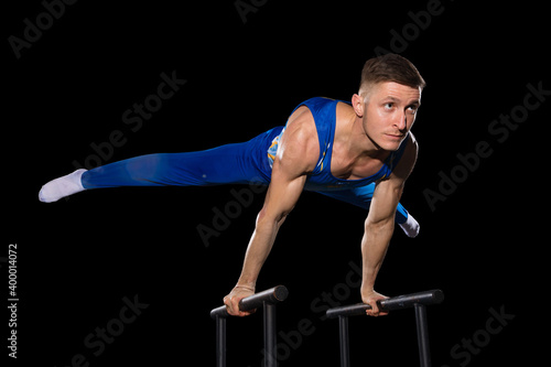 Experience. Muscular male gymnast training in gym, flexible and active. Caucasian fit guy, athlete in blue sportswear doing exercises for strength, balance. Movement, action, motion, dynamic concept.