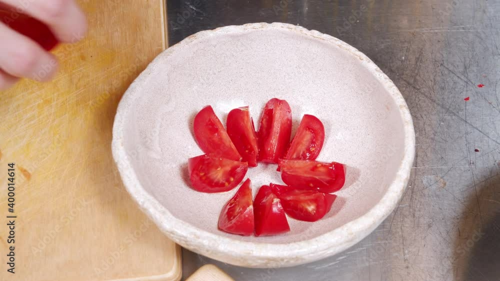 Close up of female hands laying ripe red tomato slices on plate Close up of female hands laying ripe red tomato slices on plate