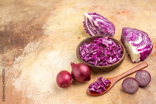 top view chopped red cabbage in a wooden bowl and several onions are ready for beet salad on a wooden background with space for text