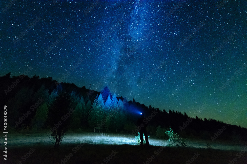 Fantastic starry night with galaxy Milky Way with a tourist and a tent on the mountain range in the Ukrainian Carpathians Fantastic starry night with galaxy Milky Way with a tourist and a tent on the mountain range in the Ukrainian Carpathians