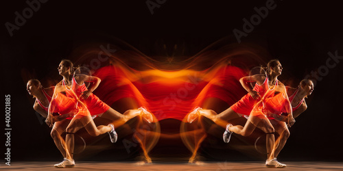 Young woman playing tennis isolated on black with fire flames. Youth, flexibility, power and energy. Reflection, mirror, strobe light. Youth, flexibility, power and energy. Negative space for ad.
