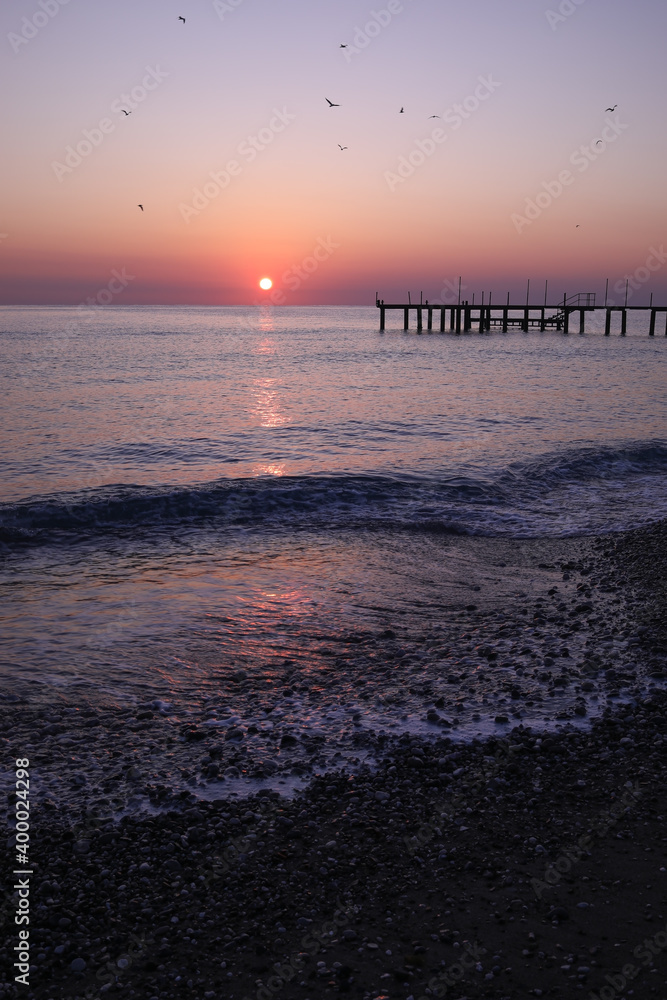 Pier silhouette on the beach at sunrise pink purple orange red skyline and background colors, relaxing holiday concept, in Antalya Turkey. Pier silhouette on the beach at sunrise pink purple orange red skyline and background colors, relaxing holiday concept, in Antalya Turkey.
