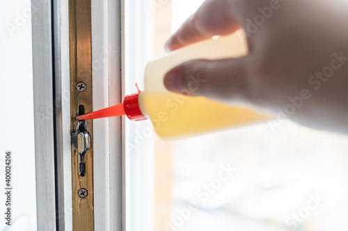 lubricating window frame mechanism with oil from oiler close up