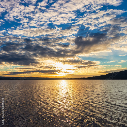 Sunset over the lake  reflection of the sun with clouds  dramatic sky and golden colors. 