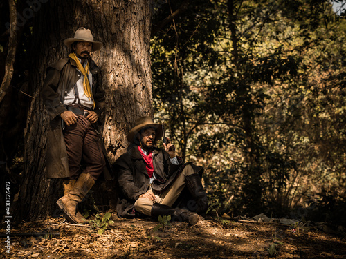 A twin senior cowboy stand and sat with a gun to guard the safety of the camp in the western area