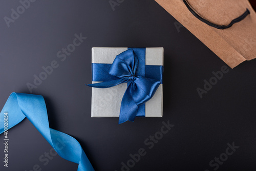 blue gift box with white ribbon on black background flat lay top shot