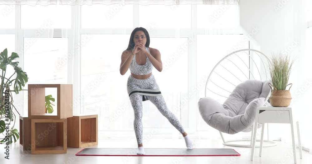 Athletic black woman engaged in sports performs stretching exercises with elastic bands, working out home training. Healthy lifestyle. Fitness. Athletic black woman engaged in sports performs stretching exercises with elastic bands, working out home training. Healthy lifestyle. Fitness.