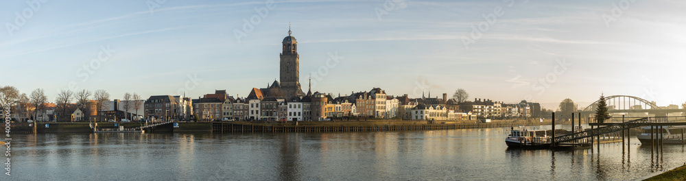 Super wide cityscape panorama of the Dutch Hanseatic medieval city of Deventer in The Netherlands seen from the other side of the river IJssel at sunrise