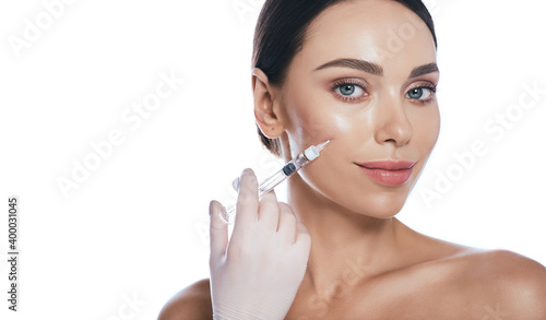 Beautician doing injections dermal fillers into female cheeks for a younger or more beautiful face. Cosmetology, filler treatment