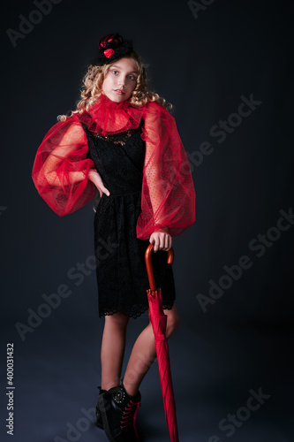 retro portrait of a girl in a black dress with a red collar and an umbrella. vintage hat. studio. dark background