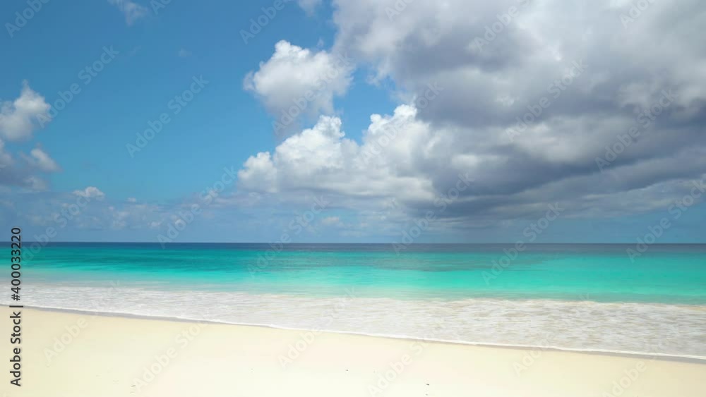 Exotic beach by the ocean with rolling waves on the sandy shore and blue sky Exotic beach by the ocean with rolling waves on the sandy shore and blue sky
