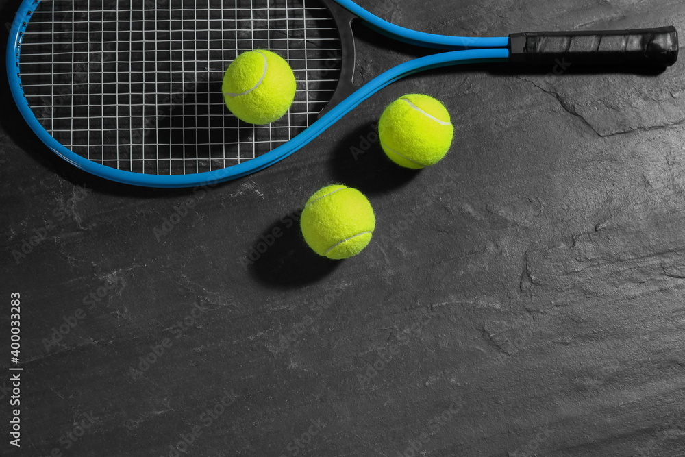 Tennis racket and balls on black table, flat lay. Sports equipment