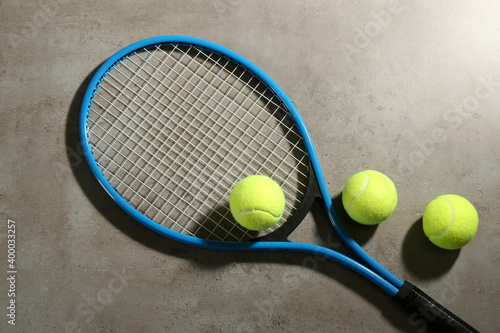 Tennis racket and balls on grey table, flat lay. Sports equipment