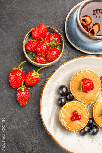 top view little yummy pancakes with fruits and cup of tea on grey desk pie cake fruit
