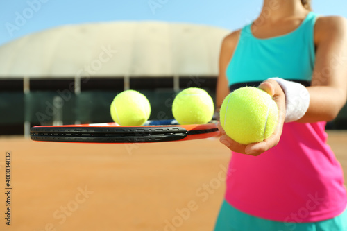 Sportswoman with racket and tennis balls at court, closeup © New Africa