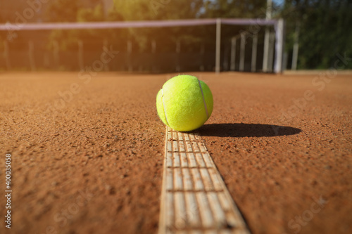 Bright yellow tennis ball on clay court © New Africa